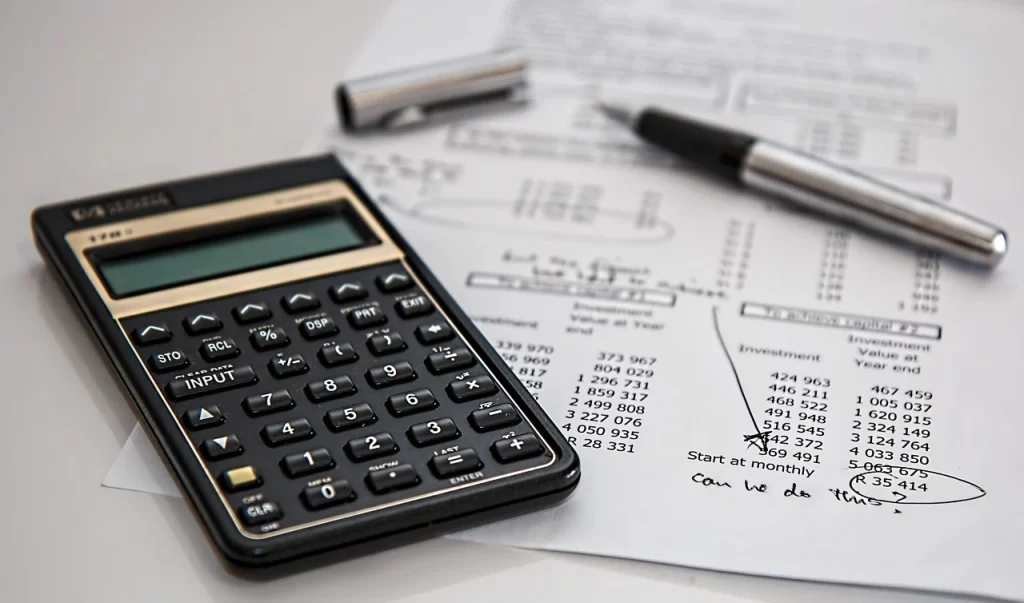 Calculadora e documentos fiscais sobre uma mesa, destacando a importância de estar atento às despesas com impostos e dicas para evitar pagar demais.